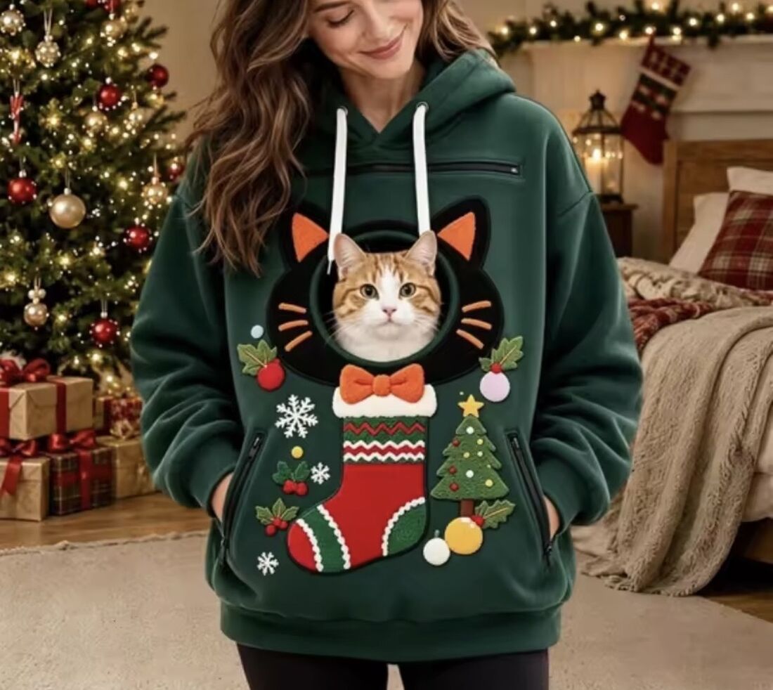 A cat looking out of the cat-ear ring on the Stocking Green hoodie
